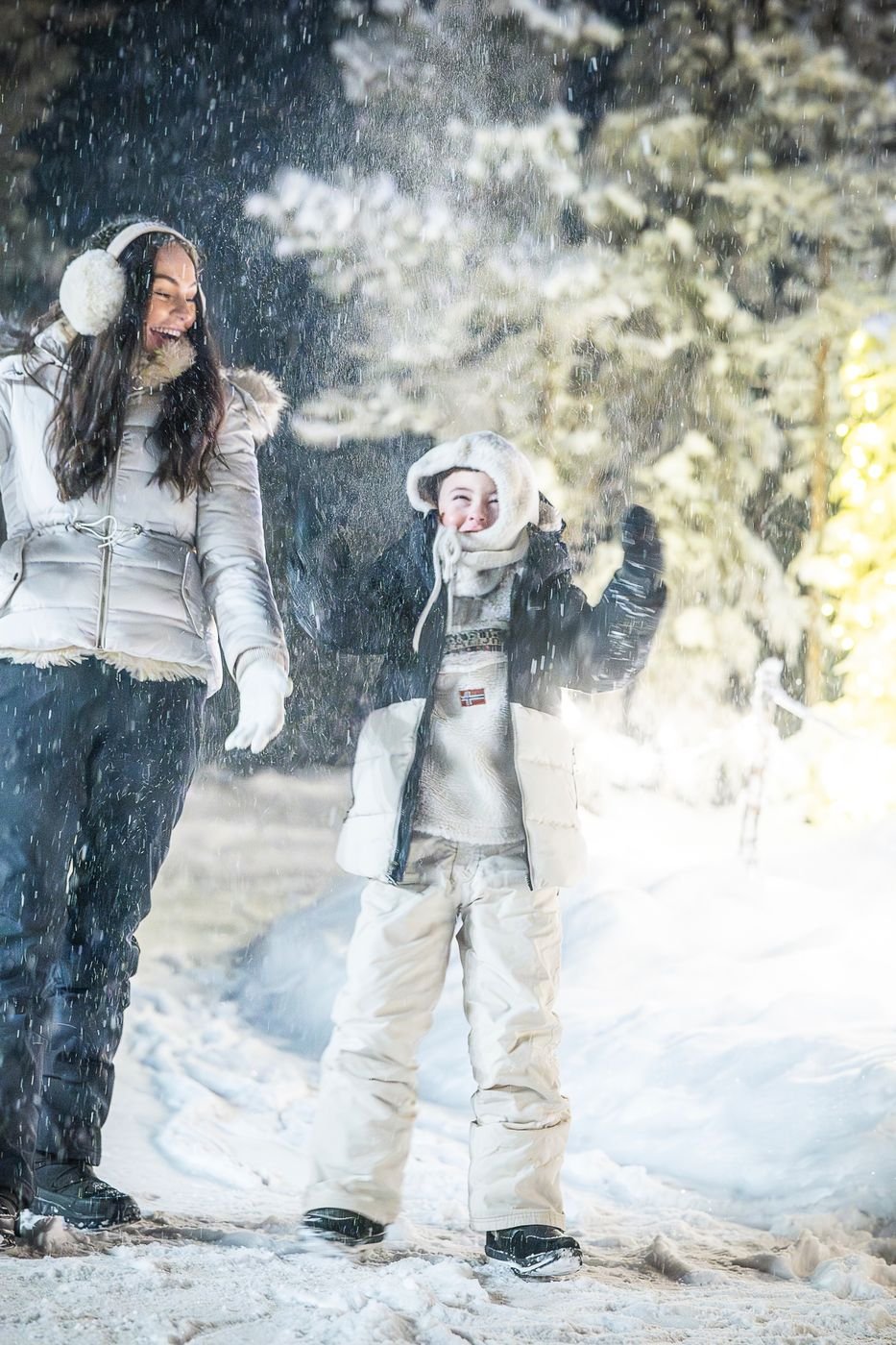 Mother and child playing in falling snow in a Lapland forest