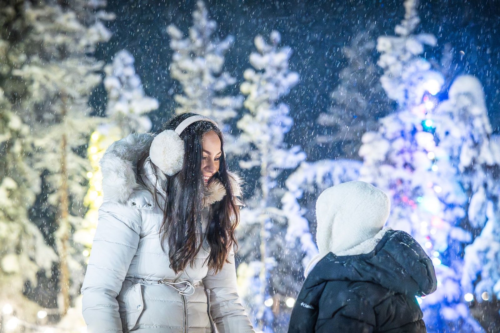 Family photography in Ylläs, Lapland: mother laughing with her child in a snowy forest