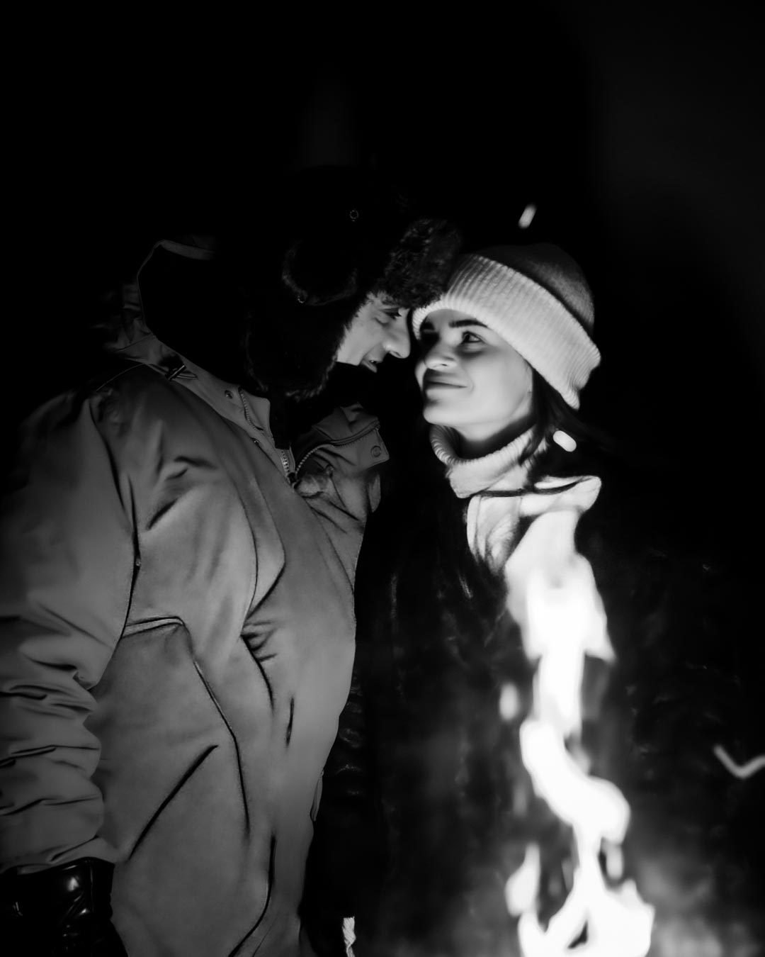 Black and white photo of a couple by a campfire at night in Lapland